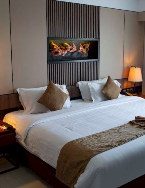 A cozy, well-lit hotel room with a large bed, two bedside lamps, a decorative headboard, and a window with curtains on the right.