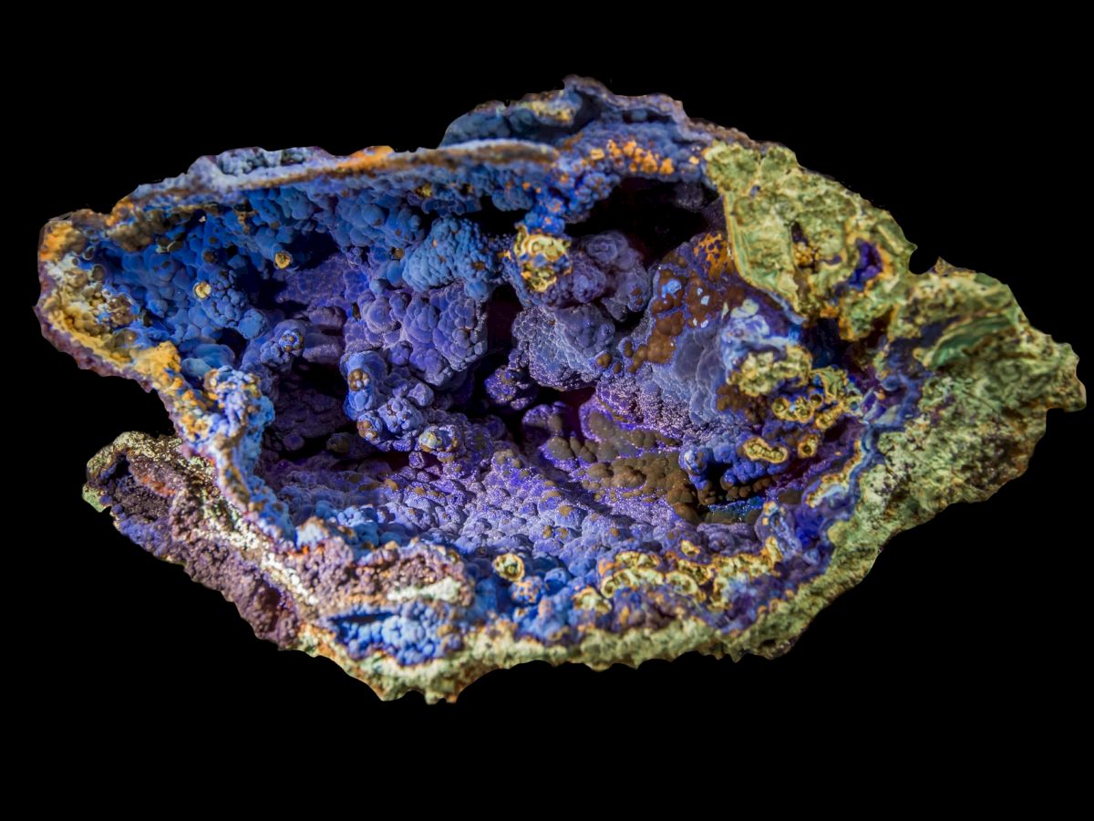 This image shows a vibrant, multicolored mineral with shades of blue, purple, green, and yellow, against a black background.