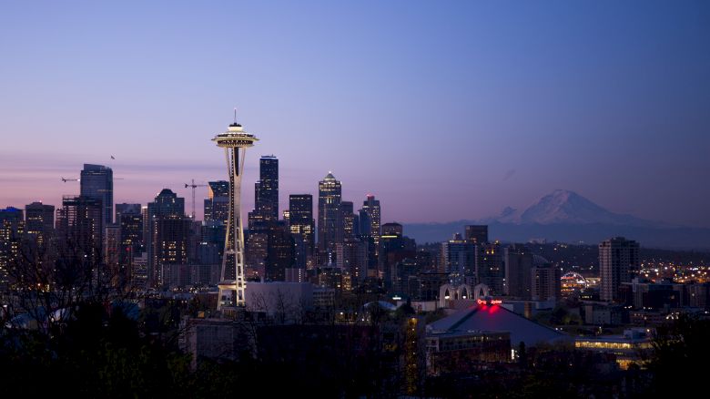 This image shows the Seattle skyline at dusk with the Space Needle prominently featured, and Mount Rainier visible in the background.